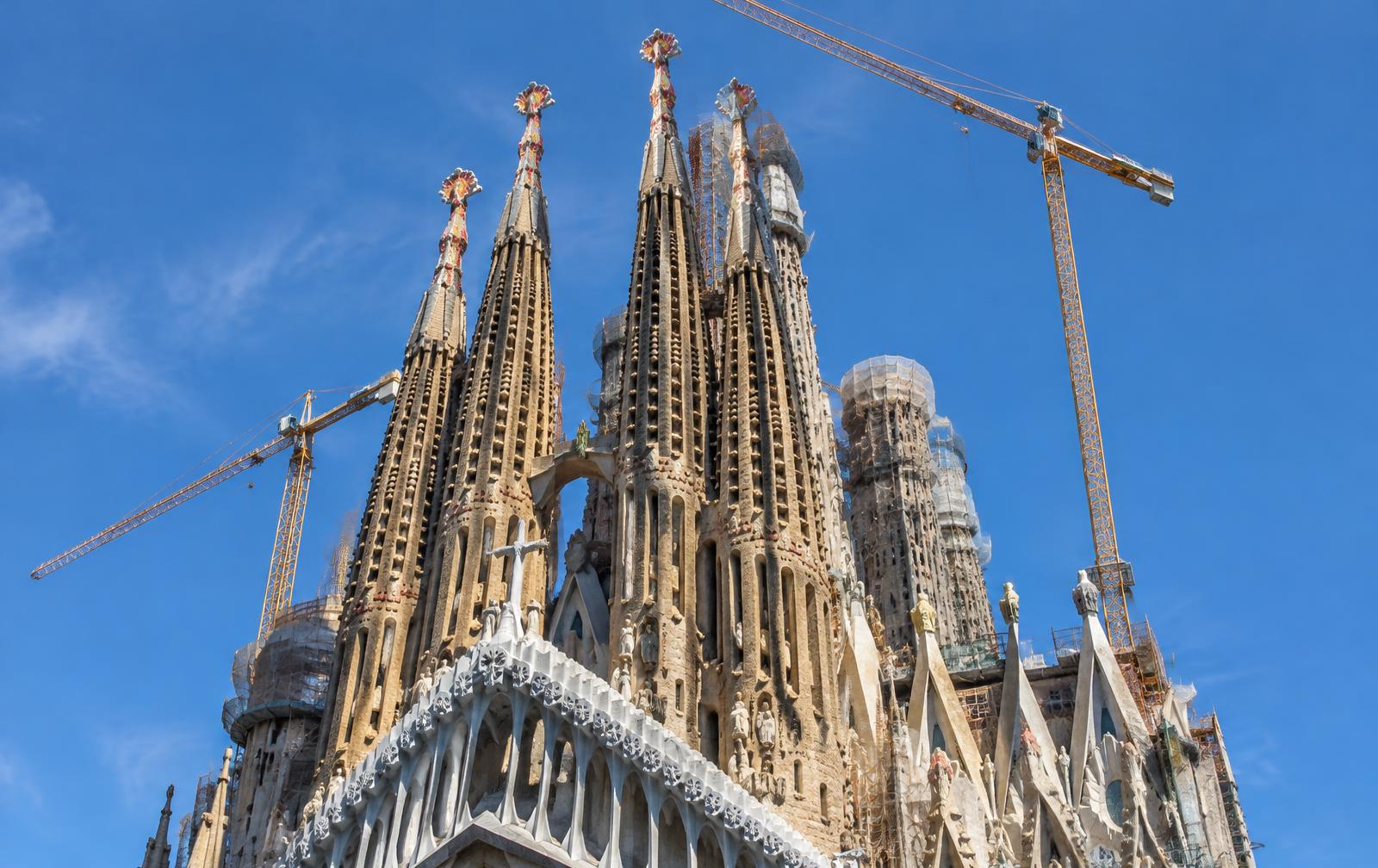 Torres de la Sagrada Família con grúas de construcción sobre un cielo azul